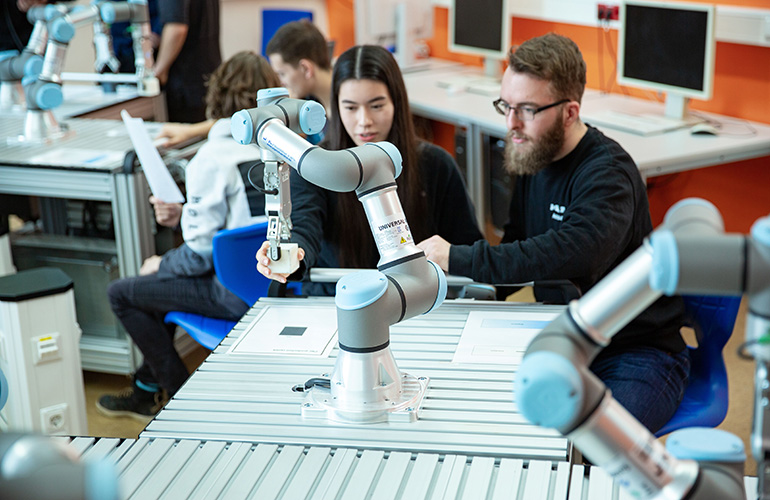 Two people learning how to program a UR cobot arm.