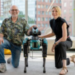 marc raibert and kate darling kneel next to a boston dynamics spot robot.